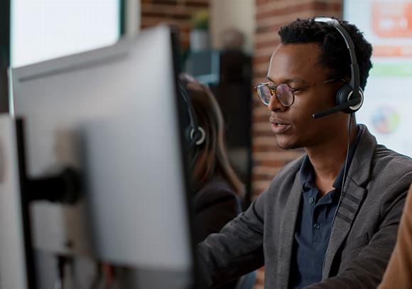 man chatting on headset looking at computer